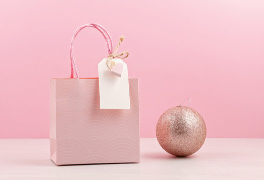 Creative image of pink gift bag with empty tag, heart and christmas decoration. Christmas shopping, sales, presents concept