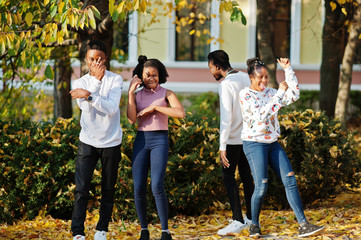Fototapeta premium Four african friends walking the streets of an ancient city at autumn sunny day.