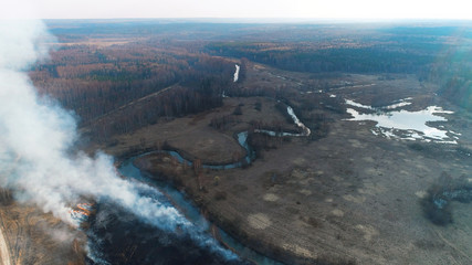 Forest and field fire. Dry grass burns, natural disaster. Aerial view. A large burned field, burning occurs on the banks of a small river.
