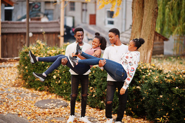 Fototapeta premium Four african friends walking the streets of an ancient city at autumn sunny day.