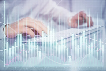 Double exposure of graph with man typing on computer in office on background. Concept of hard work. Closeup.