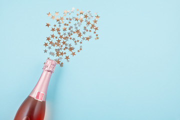 Creative photo of champagne bottle with confetti on blue background