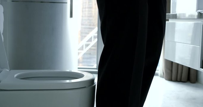 business man in trousers and shirt sit on the toilet during the day to defecate with the phone in his hands