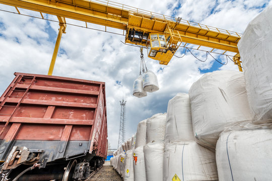 Cargo crane lifts two large bags of ammonium nitrate. Big yellow gantry crane.