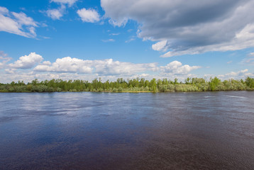 Wide river and cloudy sky. Spring landscape.