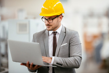 Businessman in warehouse. Young architect with helmet in suit. Close up.