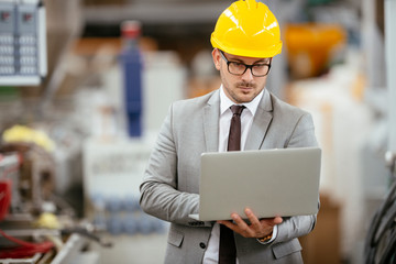Businessman in warehouse. Young architect with helmet in suit. Close up.