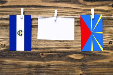 Hanging flags of El Salvador and Reunion attached to rope with clothes pins with copy space on...