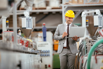 Businessman in warehouse. Young architect with helmet in suit.