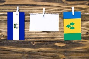 Hanging flags of El Salvador and Saint Vincent And The Grenadines attached to rope with clothes...