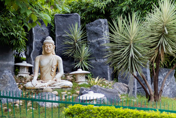 Wide shot of the front view of Buddha statue in with green railings in the foreground. Meditation concept