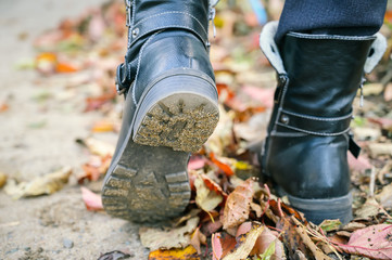 Women's boots on fallen autumn leaves.