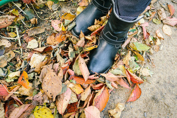 Women's boots on fallen autumn leaves.