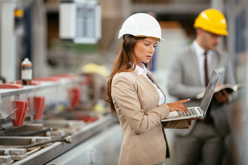 Businesswoman in warehouse. Young female architect with helmet in suit. Close up.
