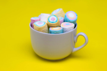 Multi-colored marshmallows in a white tea cup