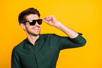 Photo of cheerful positive cool man in sunglass looking far away smiling toothily beaming holding...