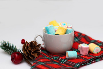 Fototapeta na wymiar Multi-colored marshmallows in a white tea cup on a checkered napkin. Christmas decor, holiday.