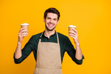 Photo of cheerful white positive toothy beaming barista hold green shirt two disposable paper cups...