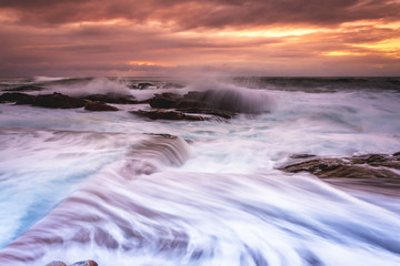 Fototapeta na wymiar Large waves wash into the tidal ocean pool at sunrise