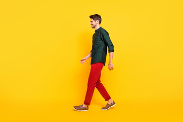 Fototapeta na wymiar Full body profile side photo of cheerful positive brunette hair guy go walk have spring weekends holidays enjoy wear youth style clothing sneakers isolated over yellow color background