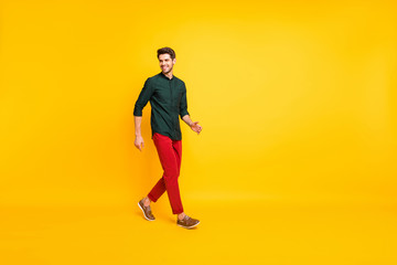 Fototapeta na wymiar Turned full length body size photo of positive cheerful handsome guy walking towards empty space with cheerful smile isolated over vibrant color background