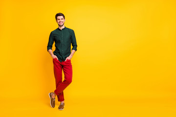 Fototapeta na wymiar Full length body size photo of posing cheerful toothy worker standing confidently with hands in pockets and legs crossed isolated over yellow vibrant color background