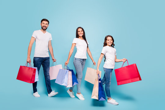 Full length photo of beautiful three people clients mom dad schoolkid with brown hair shop hold bags bargain black friday wear white t-shirt denim jeans sneakers isolated over blue color background