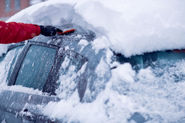 Snow covered car.Man removing snow from car