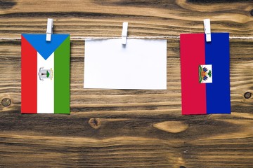 Hanging flags of Equatorial Guinea and Haiti attached to rope with clothes pins with copy space on...