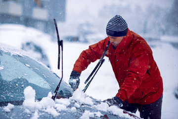 Frozen car covered snow at winter day. cleaning car windshield of snow cold winter. Man clears snow...