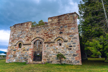 A section of the Urquhart Castle Ruins brightly illuminated by the sun with the Scottish Flag flying in the breeze.
