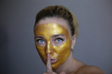 Portrait of young woman posing with golden face mask. Skin acne treatment. Golden face mask. 