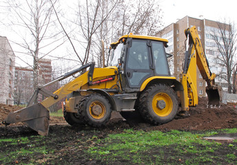 Obraz na płótnie Canvas Yellow wheeled mini digger digs a trench in the city