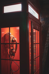 Vintage classic red illuminated telephone box in the dark
