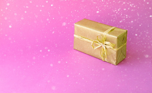 Golden box with a bow. Gift on a colored pink background. Great design for any purposes. Fashion, glamor background. New year, Christmas design