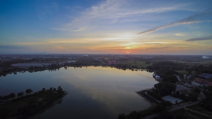 Fototapeta premium Aerial view evening above reservoir with red sun light and cloudy sky background, sunset at Krajub reservoir, Nong Kob, Ban Pong, Ratchaburi, Thailand.