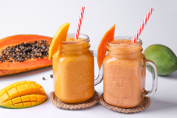 Homemade fruit smoothies made of papaya and mango on a white background, horizontal orientation