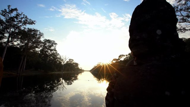 4K, A river with the head sculptures on the bridge leading to north gate at Angkor Thom temple complex at sunset ligth. Ancient devas statues carved out of stones. Moat with asura guardian statues-Dan
