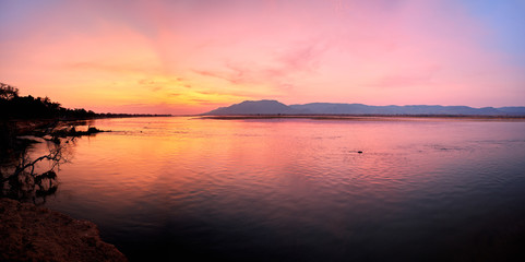 Panoramic view of sunset on the african Zambezi river. The dramatic, red sky reflects on the...