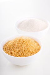 Brown natural cane sugar and white granulated sugar in white bowls
