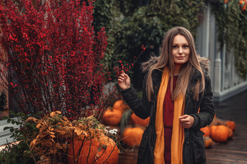 A girl walks through the autumn city. Pumpkins decorate the streets