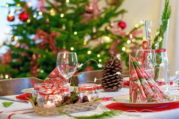 Cozy home Christmas interior, festive table arrangement and Christmas tree on the background.