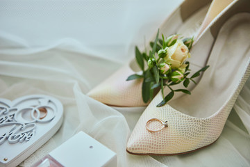 bridal accessories such as shoes, bouquet , ring and perfume lie on a table