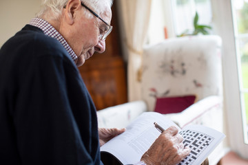 Senior Man Doing Crossword Puzzle At Home