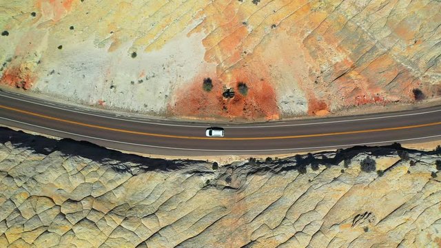 Aerial: Drone panning over van moving on highway over mountain at Grand Staircase-Escalante National Monument in desert