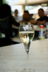 Closeup of a glass filled with prosecco with blured people behind