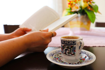 Young woman drinks Turkish coffee and reads book