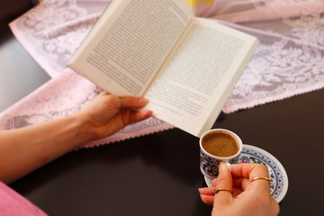 Young woman drinks Turkish coffee and reads book