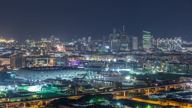 Beautiful view of bright lights from city buildings and stadium with fast rhythm at evening aerial timelapse in Financial center, Dubai, United Arab Emirates