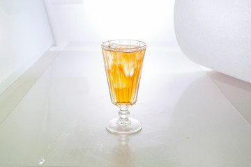glass of orange  tincture on white background